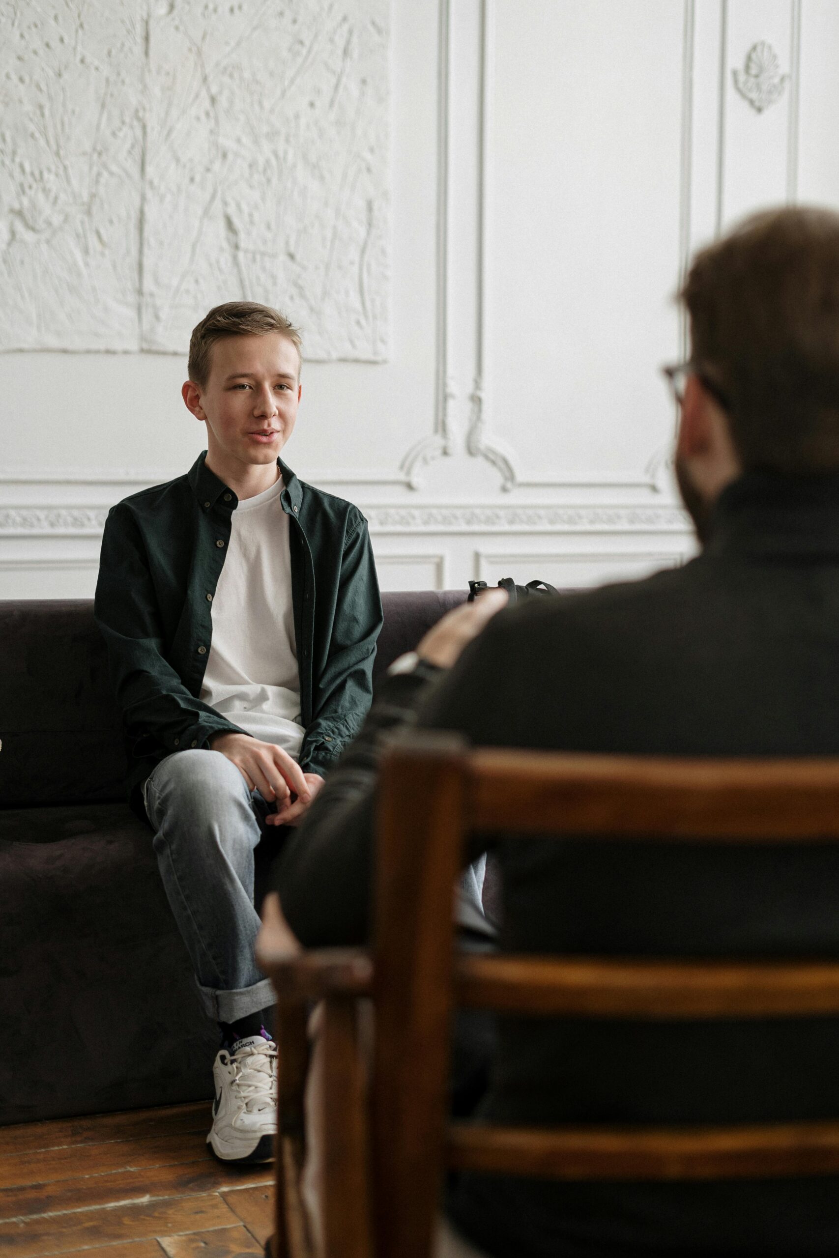 A teenager sits across from a counselor in a therapy session, promoting mental health awareness.